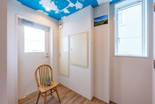 a room with a chair and a window at plat hostel keikyu sapporo sky in Sapporo