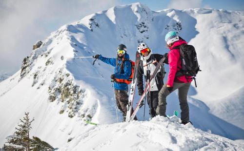 three people standing on top of a snow covered mountain at Hotel Auwirt Zentrum in Saalbach Hinterglemm