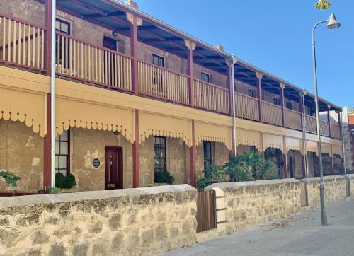 a building with a balcony on the side of it at Warders Cottage: Iconic Cottage in the Heart of Freo in Fremantle