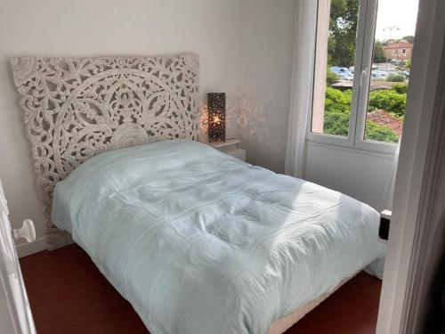 a white bed in a bedroom with a window at Petite maison de charme - Le jardin secret d'Alice in Roquebrune-sur-Argens