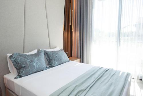 a white bed with blue pillows and a window at Enso Alaçatı in Cesme
