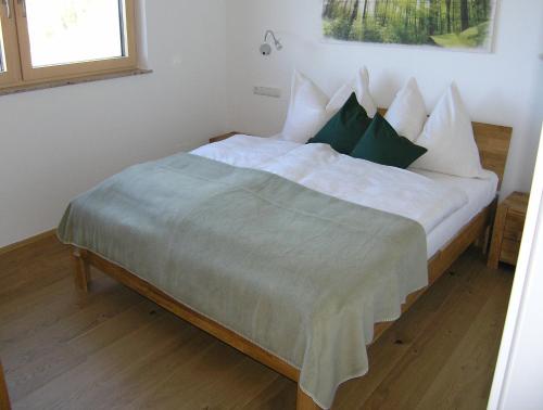 Schlafzimmer mit einem Bett mit weißer Bettwäsche und grünen Kissen in der Unterkunft Apartmenthaus STYRIA in Bad Gleichenberg