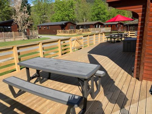 a picnic table and a bench on a wooden deck at Ben Lomond Lodge in Rowardennan