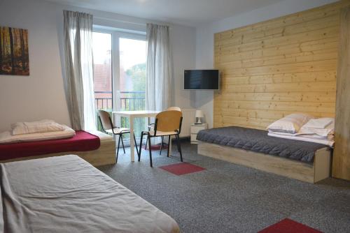 a bedroom with two beds and a table with a balcony at Dom Goscinny Skarpa in Krynica Zdrój