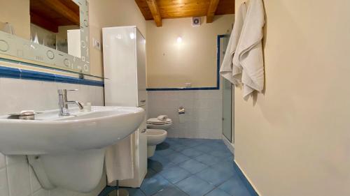 a white bathroom with a sink and a toilet at Bellavista di Magarà in Cefalù