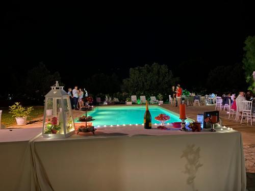 a table with a bottle of wine next to a swimming pool at Villa Piruzzu CV Torre Mulinazzo app P in Cinisi