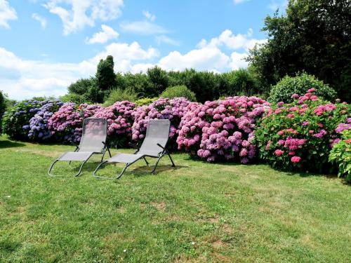 zwei Stühle vor einem Busch voller rosa Blumen in der Unterkunft Holiday Home Les Volets Rouges - PEU101 by Interhome in Peumérit
