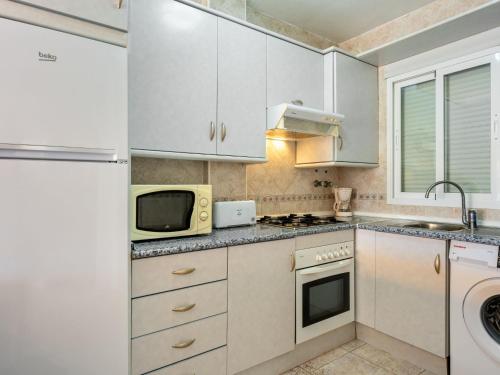 een keuken met witte kasten en een magnetron bij Apartment Sierra Mar by Interhome in Los Amarguillos