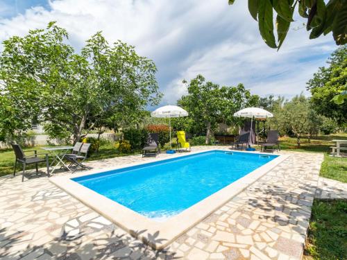 a pool with chairs and umbrellas in a yard at Apartment Villa Sandra - PUL412 by Interhome in Vodnjan