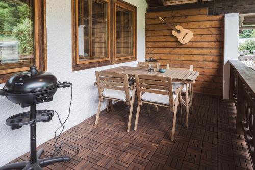 a patio with a wooden table and chairs and a grill at Ferienwohnungen Villa Salzweg in Bad Goisern