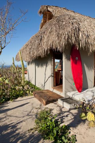a house with a thatch roof with a red surfboard on it at Hotel Escondido, Puerto Escondido, a Member of Design Hotels - Adults Only in Puerto Escondido