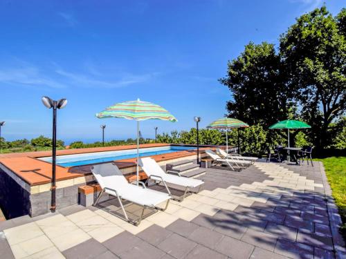 a swimming pool with lounge chairs and umbrellas at Apartment Serena by Interhome in Piedimonte Etneo