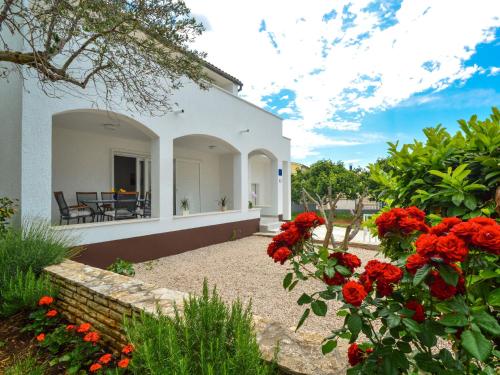 a white house with red flowers in the yard at Holiday Home Tramontana by Interhome in Sovlje