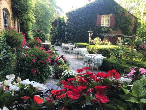 un jardin avec des fleurs rouges et blanches et un bâtiment dans l'établissement Bed & Breakfast Le Moulin Neuf, à Saint-Alvère
