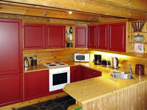 a kitchen with red cabinets and a sink and a stove at Holiday Home Kvila by Interhome in Øyuvstad
