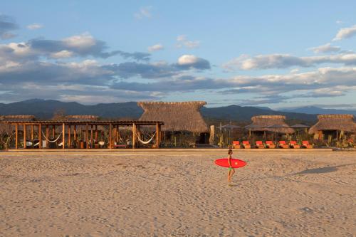 a red surfboard on the beach with a resort at Hotel Escondido, Puerto Escondido, a Member of Design Hotels - Adults Only in Puerto Escondido