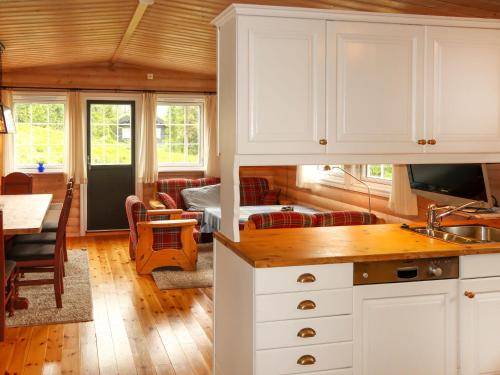 a kitchen with white cabinets and a living room at Chalet Liaråket by Interhome in Svingvoll