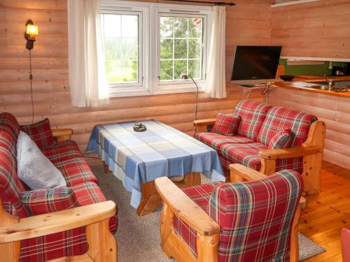 a living room with couches and a table and a tv at Chalet Liaråket - OPP209 by Interhome in Svingvoll