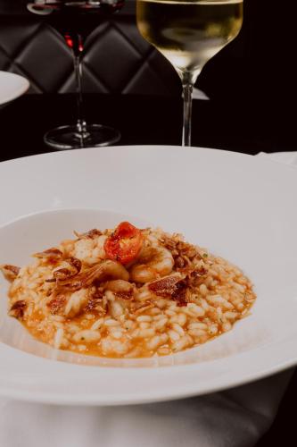 a plate of food with shrimp and a glass of wine at Bellevue Superior City Hotel in Šibenik