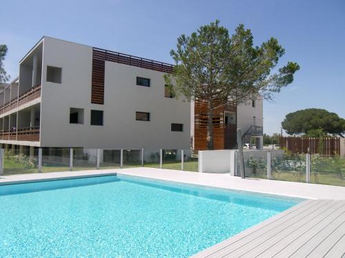 une maison avec une piscine en face d'un bâtiment dans l'établissement Apartment Le Golf Clair-13 by Interhome, à Saint-Cyprien