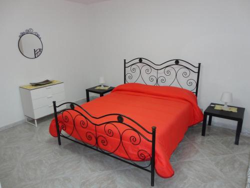 ein Schlafzimmer mit einem roten Bett mit 2 Tischen und einem Spiegel in der Unterkunft Baciati dal Sole - Appartamento in centro in Porto Empedocle