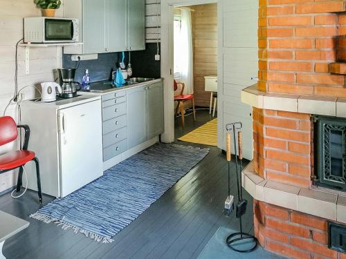 uma cozinha com armários brancos e uma parede de tijolos em Holiday Home Parkkisenniemen lomamökit by Interhome em Karvonen