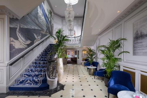 a lobby with blue stairs and plants and a chandelier at Killarney Dromhall Hotel in Killarney