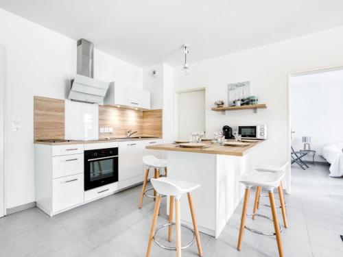 a kitchen with white cabinets and bar stools at Apartment les Terrasses de Capbreton-2 by Interhome in Capbreton