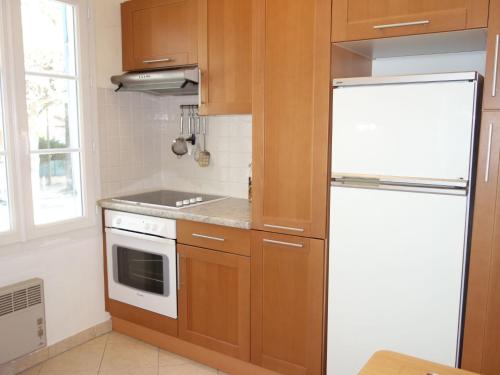 - une cuisine avec des placards en bois et un réfrigérateur blanc dans l'établissement Studio Les Nautiles by Interhome, à La Madrague