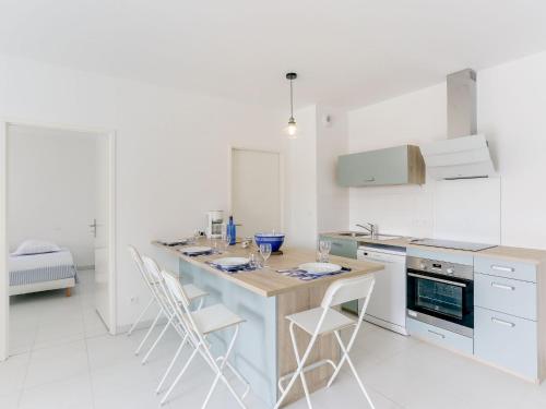 una cocina con armarios blancos y una isla con sillas en Apartment les Terrasses de Capbreton-1 by Interhome, en Capbreton