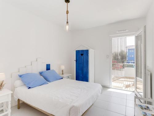 a white bed with blue pillows in a white room at Apartment les Terrasses de Capbreton-1 by Interhome in Capbreton