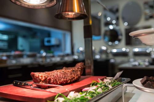 a piece of meat on a red cutting board with salad at Radisson Blu Hotel, Addis Ababa in Addis Ababa