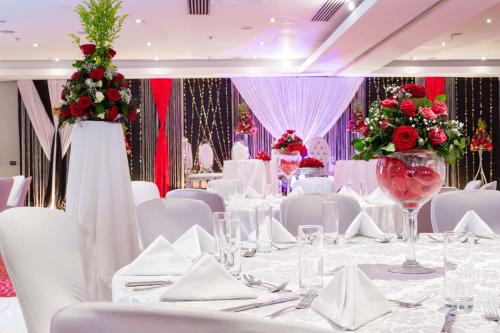 a wedding banquet room with white tables and red flowers at Radisson Blu Hotel, Addis Ababa in Addis Ababa