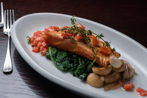 a white plate with fish and vegetables on a table at Radisson Blu Hotel, Addis Ababa in Addis Ababa