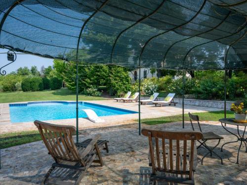 a patio with a table and chairs under a green umbrella at Holiday Home Villa Remotti by Interhome in Fubine