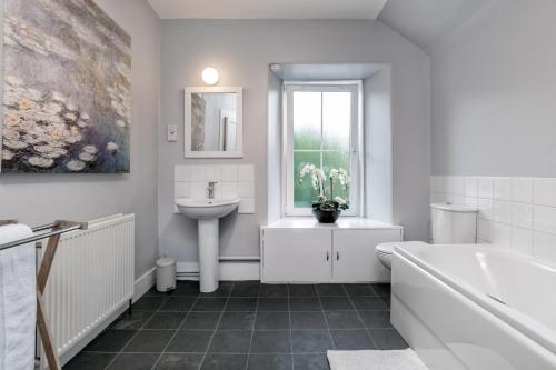 a white bathroom with a sink and a tub and a toilet at The Green Inn Rooms in Ballater