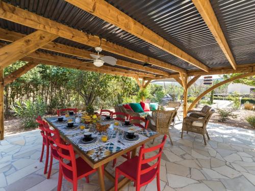 une table à manger et des chaises sous une pergola en bois dans l'établissement Villa Natlea by Interhome, à Porto-Vecchio