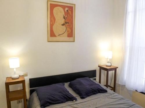 a bedroom with a bed with two lamps and a painting on the wall at Apartment Vieux Nice by Interhome in Nice