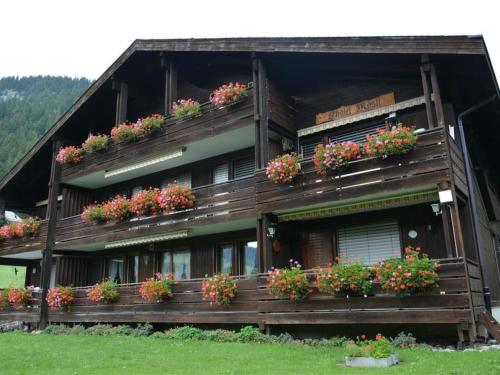a building with potted plants and flowers on it at Apartment Mösli - Zimmerli by Interhome in Zweisimmen