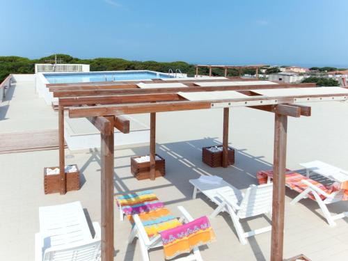 a wooden table and chairs on a roof with a pool at Apartment Superior-4 by Interhome in San Vincenzo
