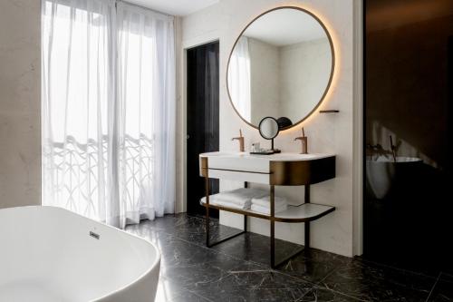 a bathroom with a mirror and a sink and a tub at Radisson Collection Hotel, Magdalena Plaza Sevilla in Seville