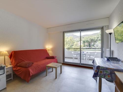 een woonkamer met een rode bank en een tafel bij Studio Sémaphore-2 by Interhome in Cavalaire-sur-Mer
