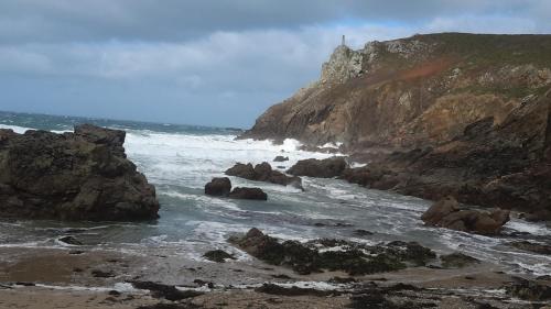 una spiaggia con rocce e l'oceano con un faro di Le Chat Bleu a Pont-Croix