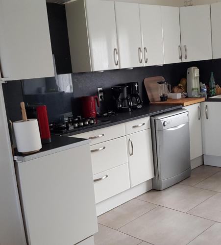 une cuisine avec des armoires blanches et un four à plaques de cuisson dans l'établissement Le Chat Bleu, à Pont-Croix