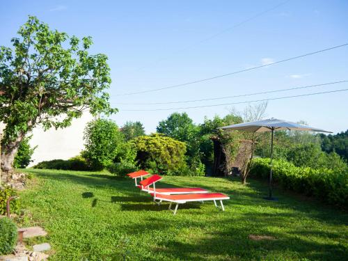 tre panche rosse sedute nell'erba con un ombrello di Holiday Home la Vallia by Interhome a Piea