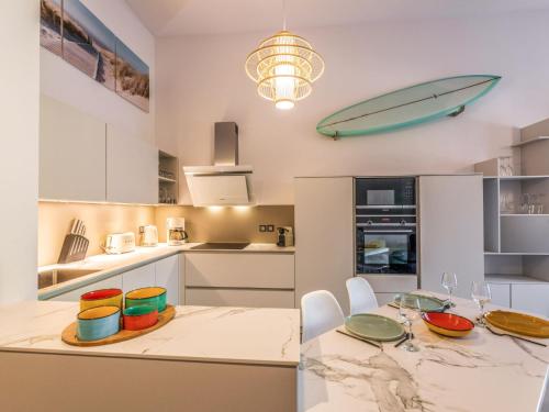 a kitchen with a table and a surfboard on the wall at Apartment Domaine Aïga-1 by Interhome in Soorts-Hossegor