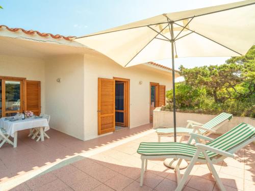 un patio con tavolo, due sedie e ombrellone di Holiday Home Turriga by Interhome a Aglientu