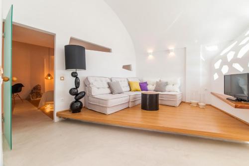 a living room with a white couch and a tv at Armeni Village in Oia