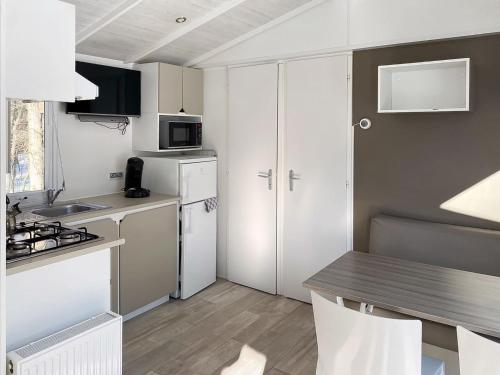 una cocina con armarios blancos y una mesa con sillas. en Holiday Home De Brenkberg-1 en Schinveld