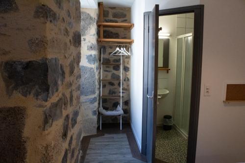 a hallway leading to a bathroom with a stone wall at Hôtel Restaurant Le Bardière in Laguiole